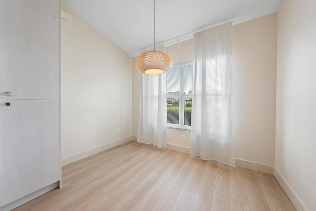 spare room with light wood-type flooring and lofted ceiling