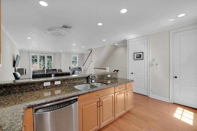 kitchen with dark stone counters, dishwasher, open floor plan, light wood-style floors, and a sink