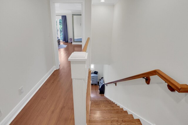 stairway featuring crown molding, baseboards, and wood finished floors