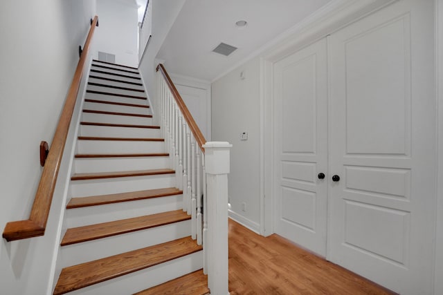 stairs featuring crown molding, wood finished floors, visible vents, and baseboards