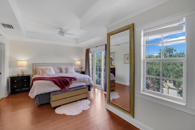 bedroom with hardwood / wood-style flooring, visible vents, access to exterior, baseboards, and a raised ceiling