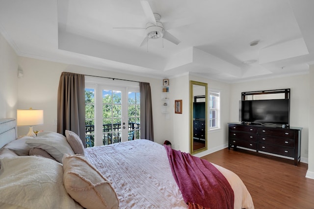 bedroom with access to outside, a tray ceiling, and dark wood-style flooring