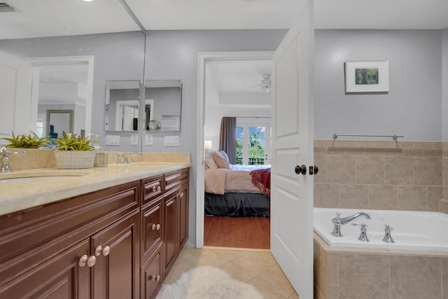 bathroom featuring double vanity, ensuite bathroom, a sink, tile patterned flooring, and a bath