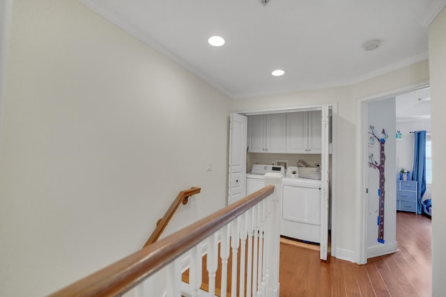 corridor with ornamental molding, wood finished floors, washing machine and clothes dryer, an upstairs landing, and recessed lighting