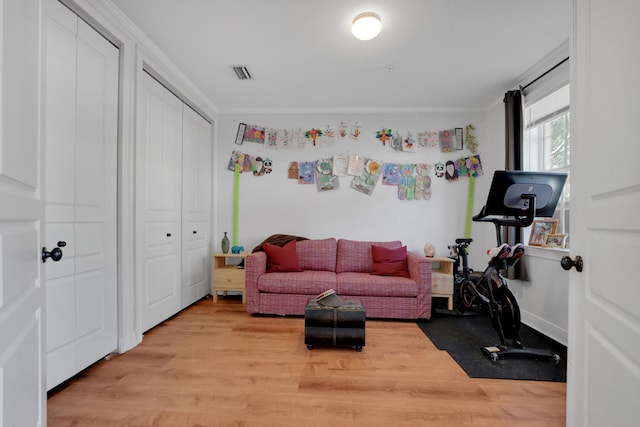 workout area featuring ornamental molding, visible vents, and light wood-style floors