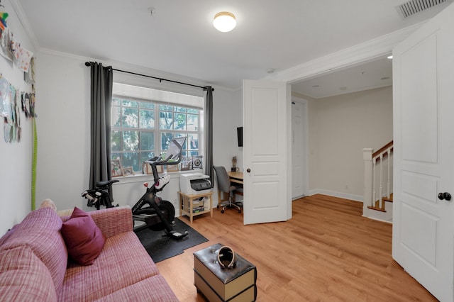 living area featuring crown molding, visible vents, wood finished floors, baseboards, and stairs