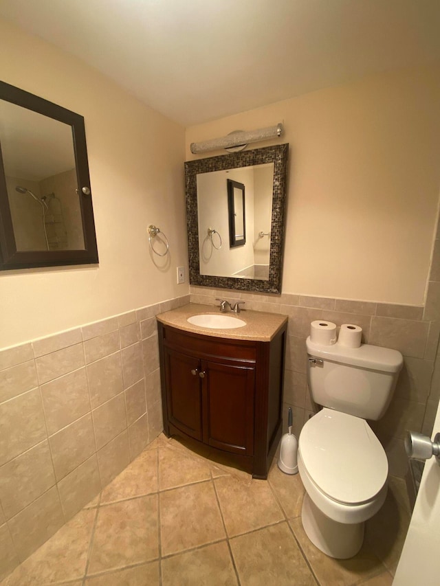 bathroom featuring tile patterned flooring, vanity, toilet, and tile walls