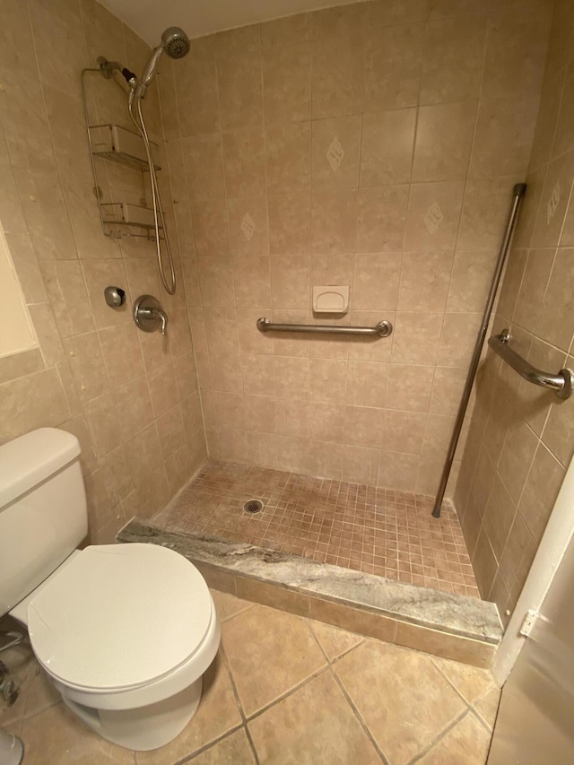 bathroom with a tile shower, toilet, and tile walls