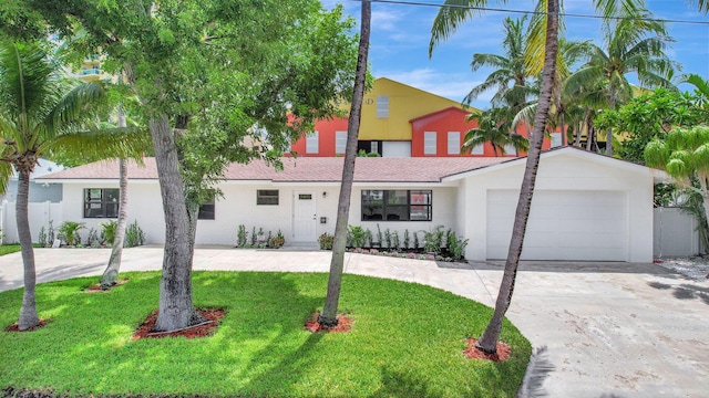 view of front of property with a garage, concrete driveway, a front lawn, and fence