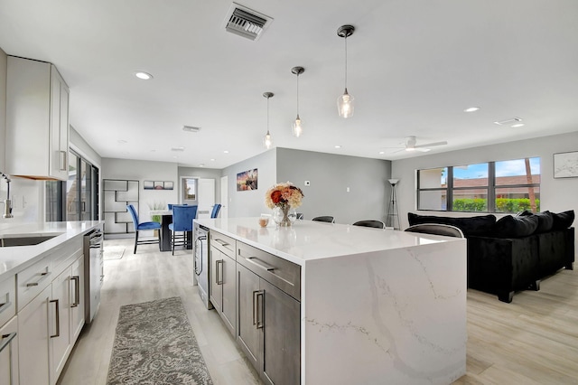 kitchen with a center island, sink, light hardwood / wood-style flooring, ceiling fan, and hanging light fixtures