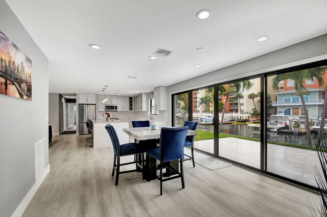 dining space with light hardwood / wood-style flooring and a water view