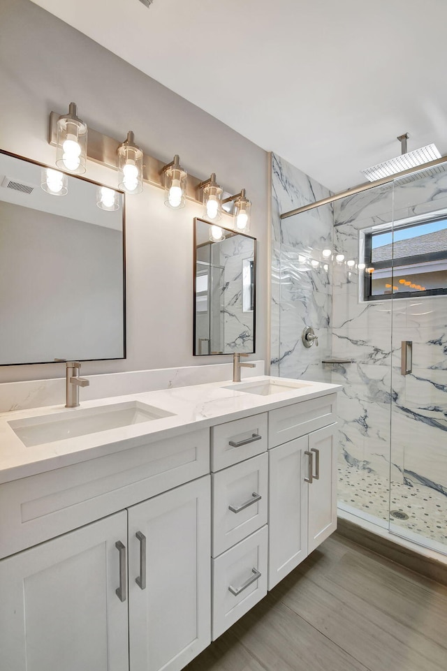 full bathroom with a marble finish shower, double vanity, a sink, and visible vents