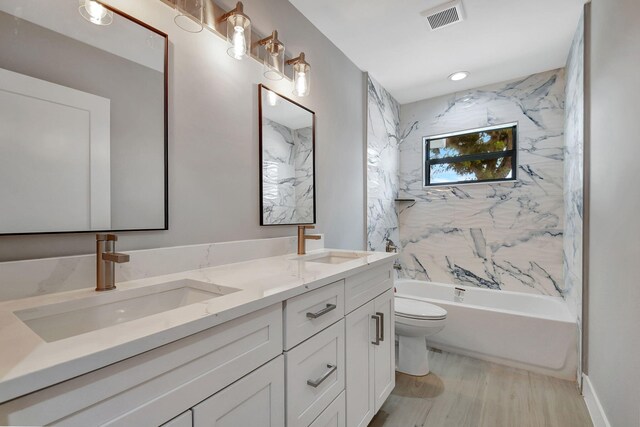 full bathroom featuring wood-type flooring, tiled shower / bath, toilet, and vanity