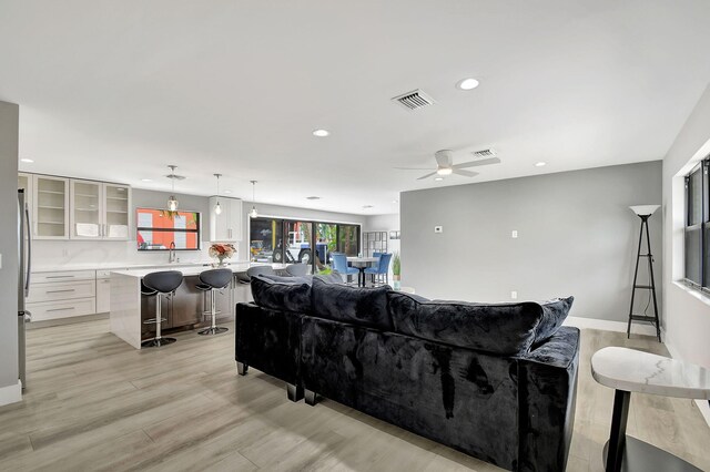 living room with ceiling fan, light hardwood / wood-style flooring, and sink