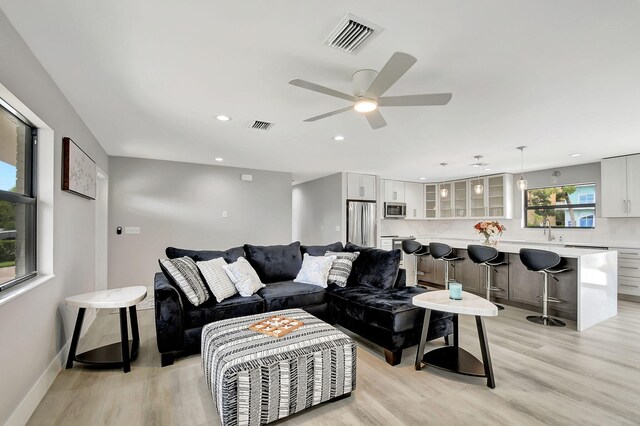 living room with ceiling fan, light hardwood / wood-style flooring, and sink