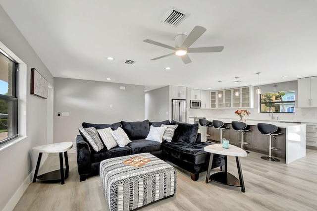 living area featuring light wood-style flooring, visible vents, and baseboards