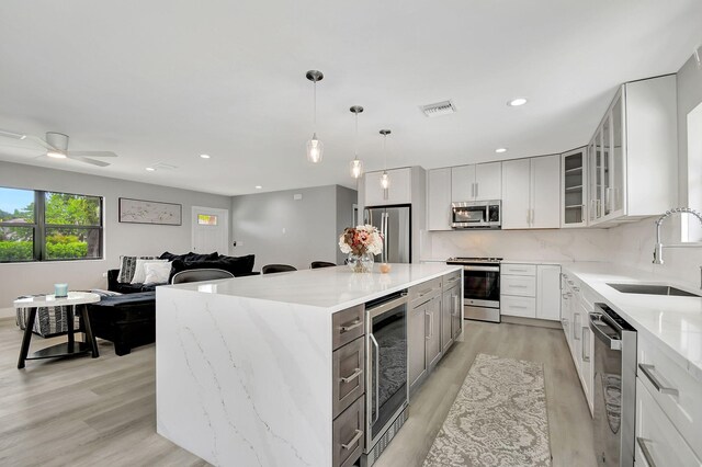 kitchen with light hardwood / wood-style flooring, tasteful backsplash, sink, a center island, and stainless steel appliances