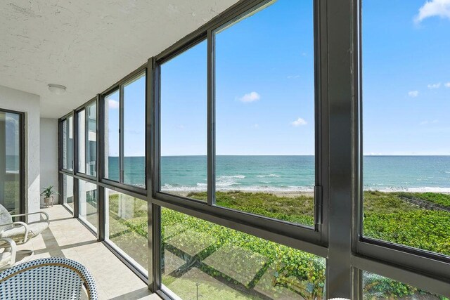 unfurnished sunroom with a view of the beach and a water view