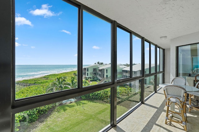 sunroom / solarium with a view of the beach and a water view