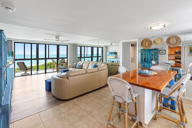 dining room with ceiling fan, light wood-type flooring, and a water view