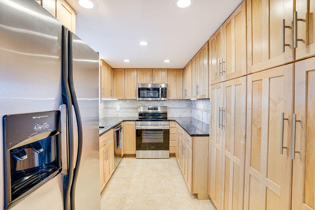 kitchen with dark stone counters, tasteful backsplash, stainless steel appliances, and light brown cabinets