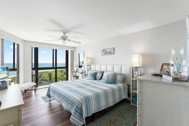 bedroom with dark hardwood / wood-style flooring, ceiling fan, and a water view