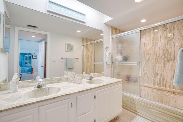 bathroom featuring a shower with door and vanity