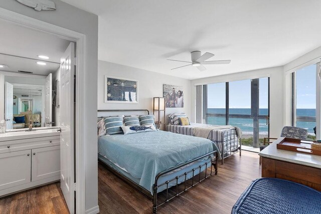 bedroom with dark wood-type flooring, a water view, and ceiling fan