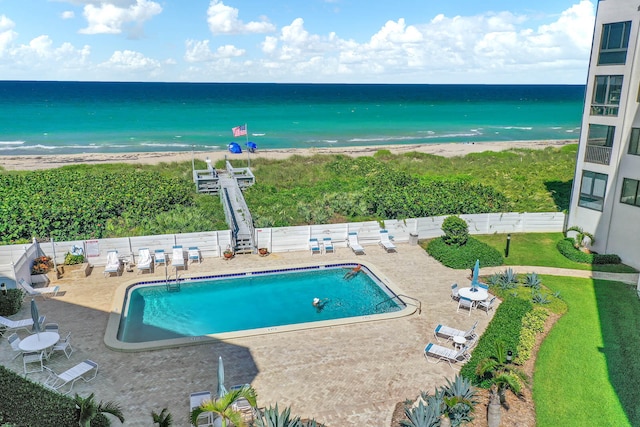 view of swimming pool featuring a water view, a beach view, and a patio area