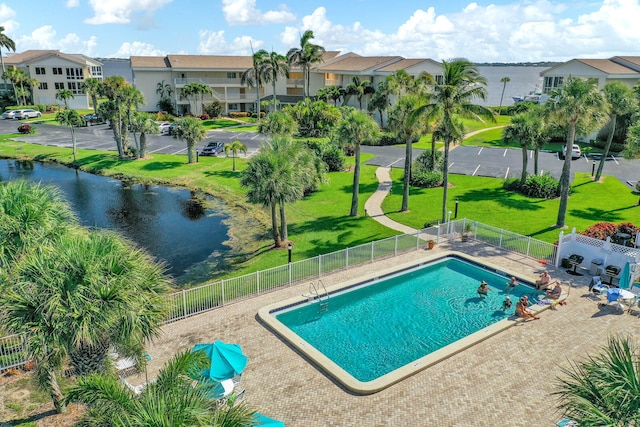 view of pool with a water view and a lawn