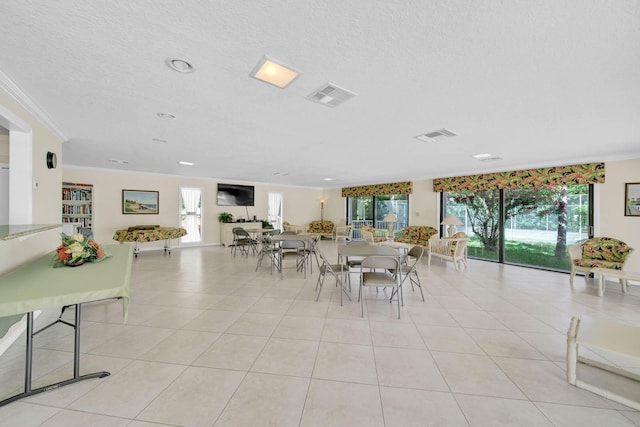 dining area with a textured ceiling, ornamental molding, and light tile patterned flooring