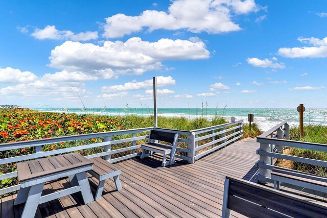 wooden deck featuring a water view and a view of the beach