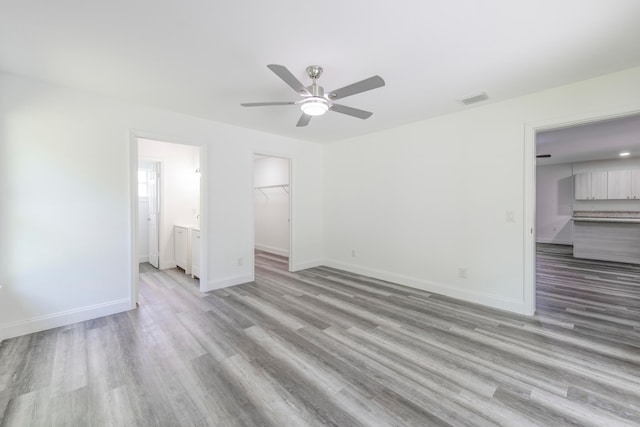 unfurnished bedroom with light hardwood / wood-style flooring, ensuite bath, ceiling fan, a closet, and a spacious closet