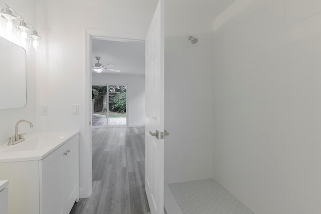 bathroom with tiled shower, vanity, ceiling fan, and hardwood / wood-style flooring