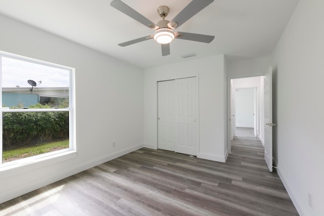 unfurnished bedroom with ceiling fan, a closet, and dark hardwood / wood-style flooring