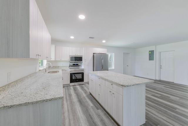 kitchen featuring a center island, stainless steel appliances, sink, and light wood-type flooring