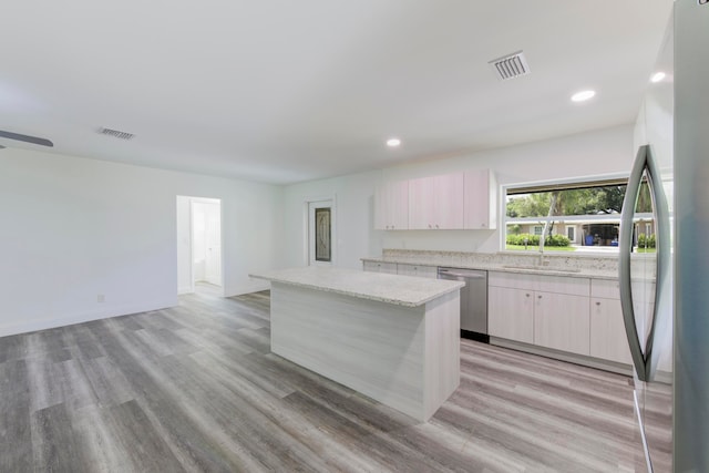 kitchen featuring light hardwood / wood-style flooring, stainless steel appliances, light stone counters, and a center island