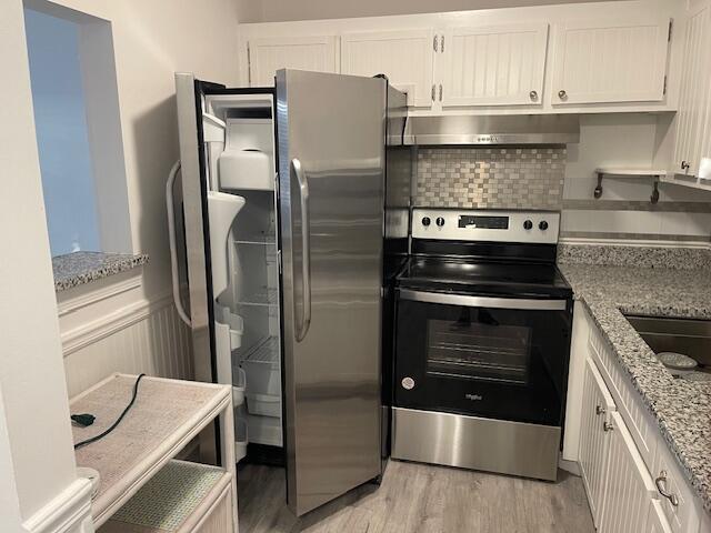 kitchen featuring stainless steel range with electric cooktop, light stone counters, white cabinets, and sink