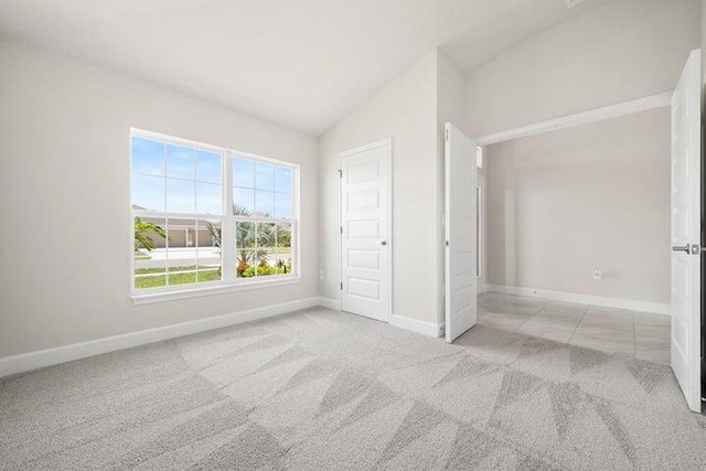 unfurnished bedroom with a closet, light colored carpet, and vaulted ceiling