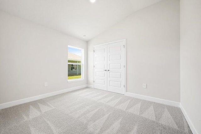 unfurnished bedroom with a closet, carpet, and vaulted ceiling