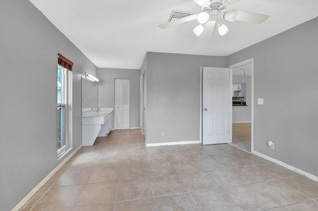 interior space with a textured ceiling, ceiling fan, and light tile patterned floors