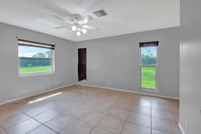 empty room with a textured ceiling, light tile patterned floors, and ceiling fan