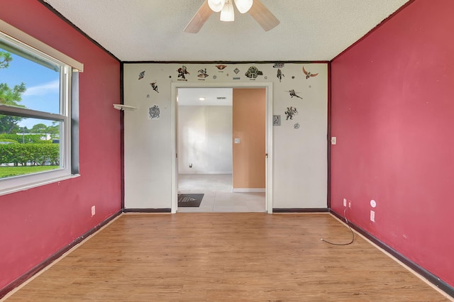 spare room with light wood-type flooring, a textured ceiling, and ceiling fan