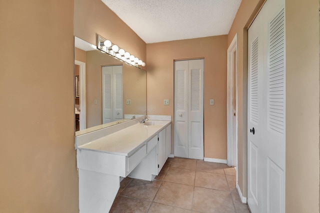 5020 Petal Pl Unit D, Delray Beach, FL 33484 - bathroom featuring a closet, vanity, tile patterned flooring, and a textured ceiling