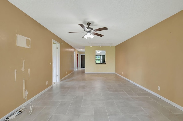 spare room with rail lighting, a textured ceiling, ceiling fan, and light tile patterned floors