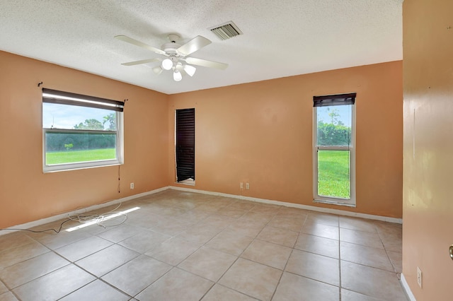 unfurnished room featuring a textured ceiling, a wealth of natural light, ceiling fan, and light tile patterned floors