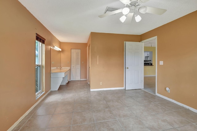 empty room featuring ceiling fan, a textured ceiling, and light tile patterned floors