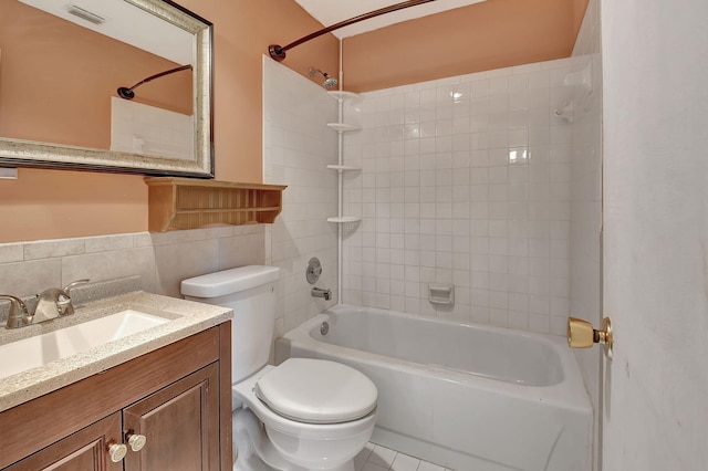 full bathroom featuring tile patterned flooring, tiled shower / bath, vanity, toilet, and tile walls