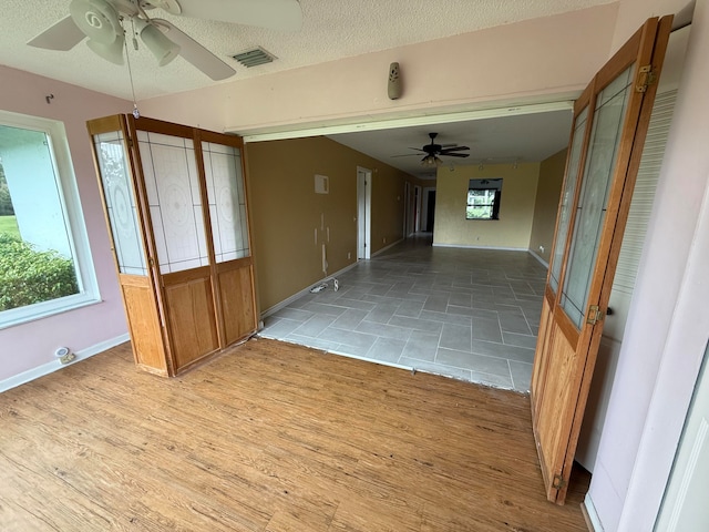 empty room featuring a textured ceiling, ceiling fan, and light hardwood / wood-style flooring