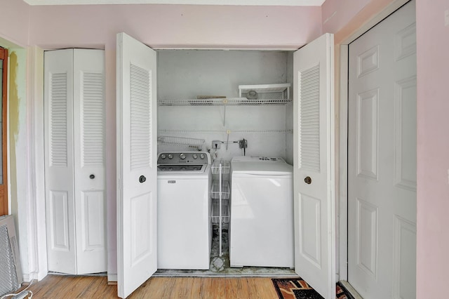 laundry area featuring washer and clothes dryer and light hardwood / wood-style floors